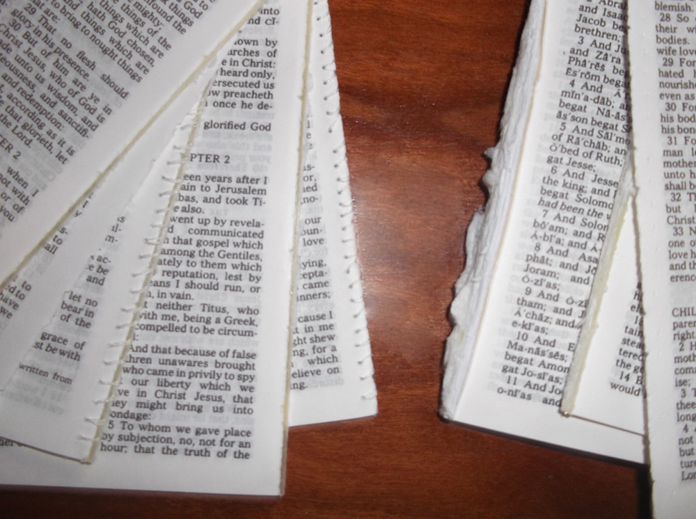 Several New Testament books, separated and spread across a desk. Some are sewn together and some are still attached with the remnants of a glue spine.